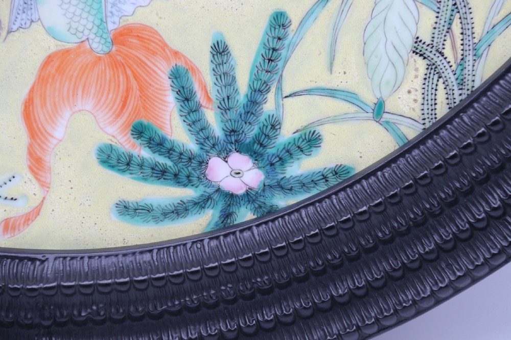 A circular framed Chinese porcelain plaque featuring vibrant hand-painted goldfish and lotus flowers on a yellow background enclosed in a carved dark frame. View XIII