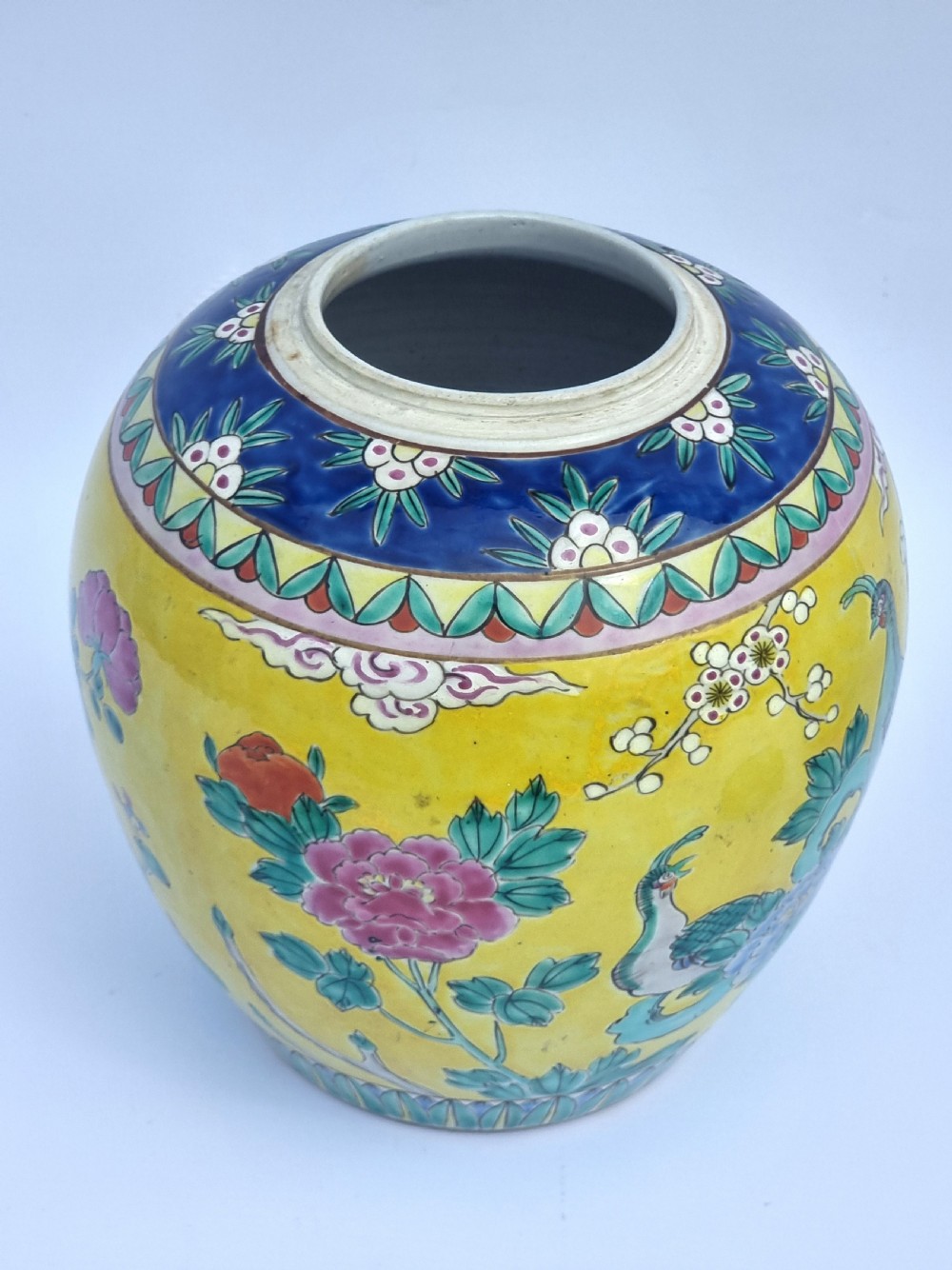 A matching pair of yellow porcelain ginger jars featuring hand-painted blue and turquoise phoenixes among peonies and floral branches, topped with deep blue decorated lids. View X
