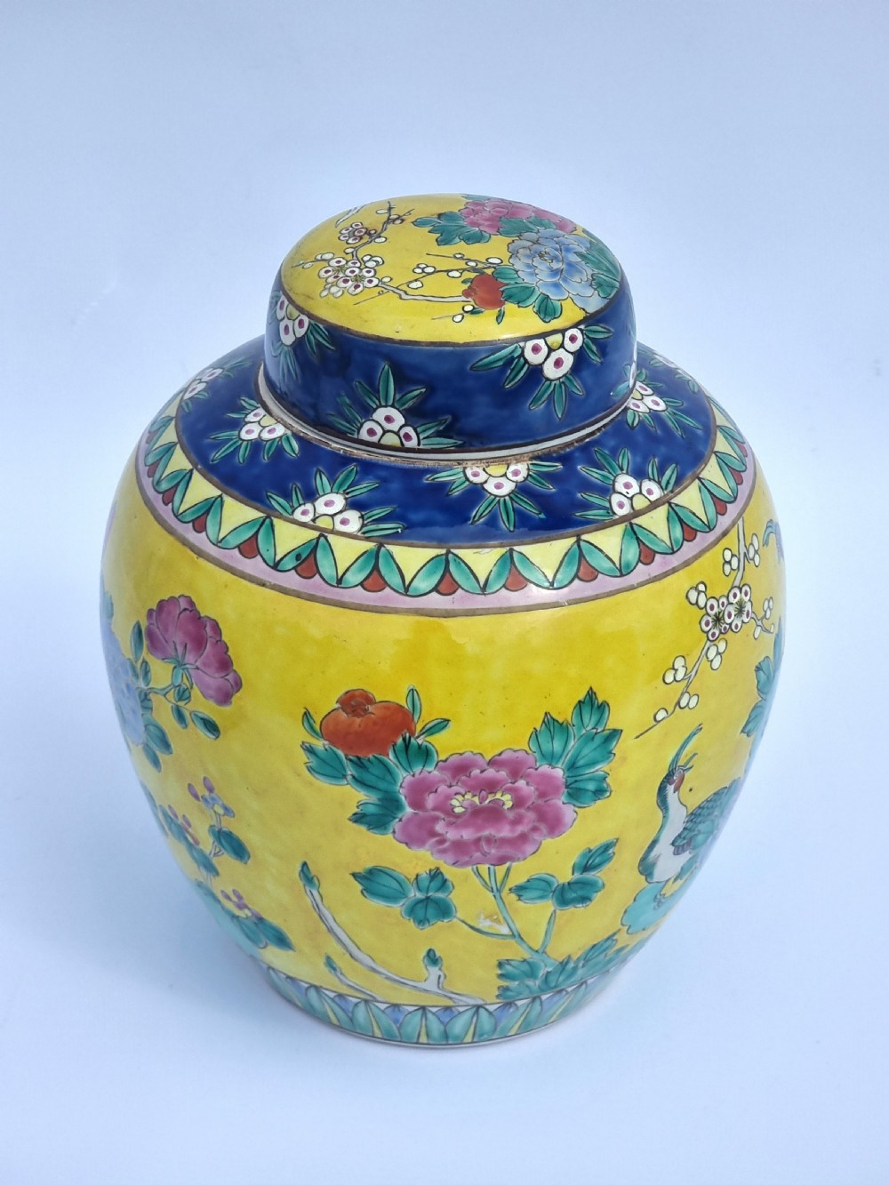 A matching pair of yellow porcelain ginger jars featuring hand-painted blue and turquoise phoenixes among peonies and floral branches, topped with deep blue decorated lids. View XXI