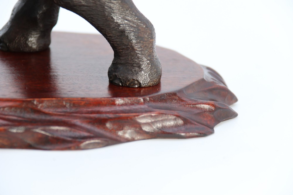 A dark patinated bronze sculpture depicting an elephant defending itself against two attacking tigers, mounted on a contoured wooden base. View XIII