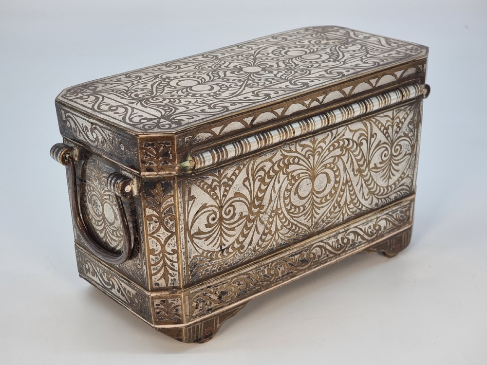 A rectangular dark bronze box featuring elaborate silver scrollwork inlay, side carrying handles, and small bracket feet. View III
