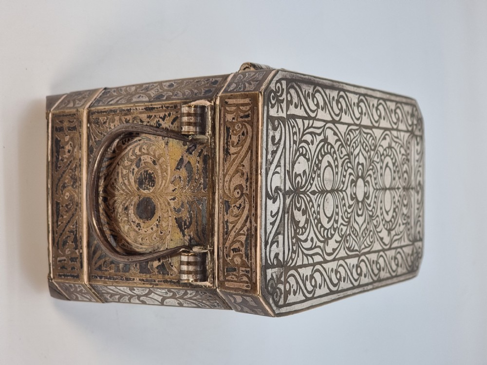 A rectangular dark bronze box featuring elaborate silver scrollwork inlay, side carrying handles, and small bracket feet. View VI