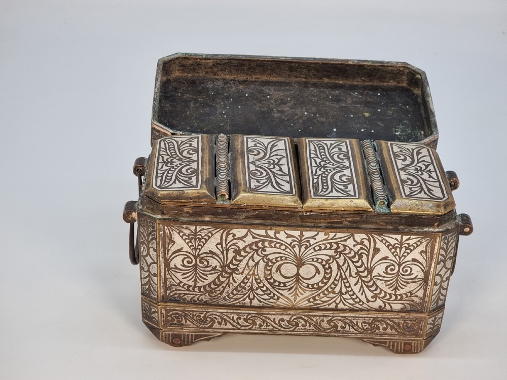 A rectangular dark bronze box featuring elaborate silver scrollwork inlay, side carrying handles, and small bracket feet. View IX