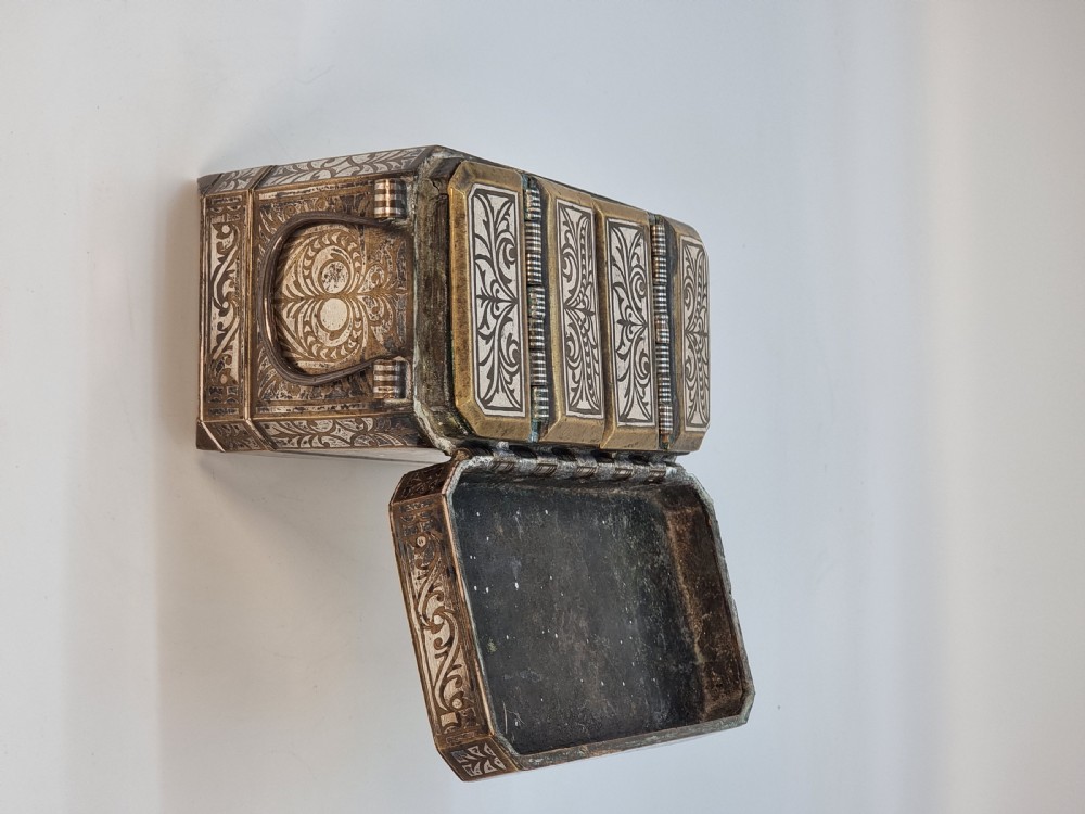 A rectangular dark bronze box featuring elaborate silver scrollwork inlay, side carrying handles, and small bracket feet. View XI