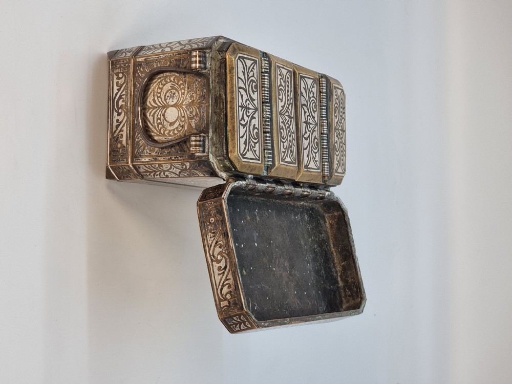 A rectangular dark bronze box featuring elaborate silver scrollwork inlay, side carrying handles, and small bracket feet. View XII