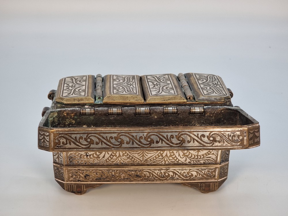 A rectangular dark bronze box featuring elaborate silver scrollwork inlay, side carrying handles, and small bracket feet. View XV