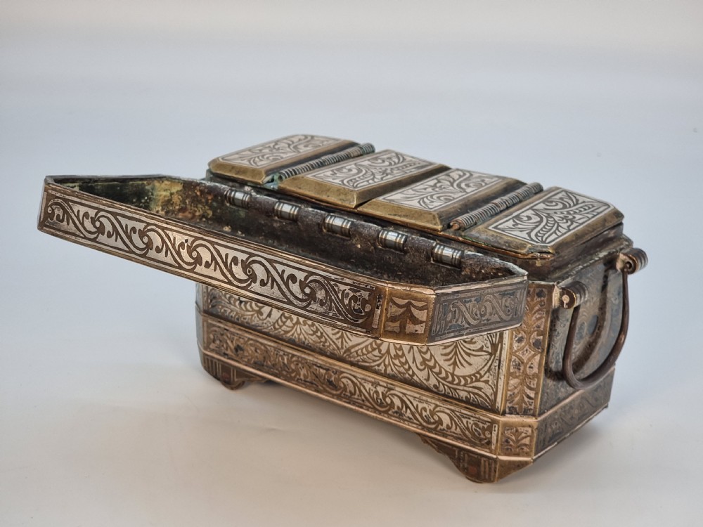 A rectangular dark bronze box featuring elaborate silver scrollwork inlay, side carrying handles, and small bracket feet. View XVII