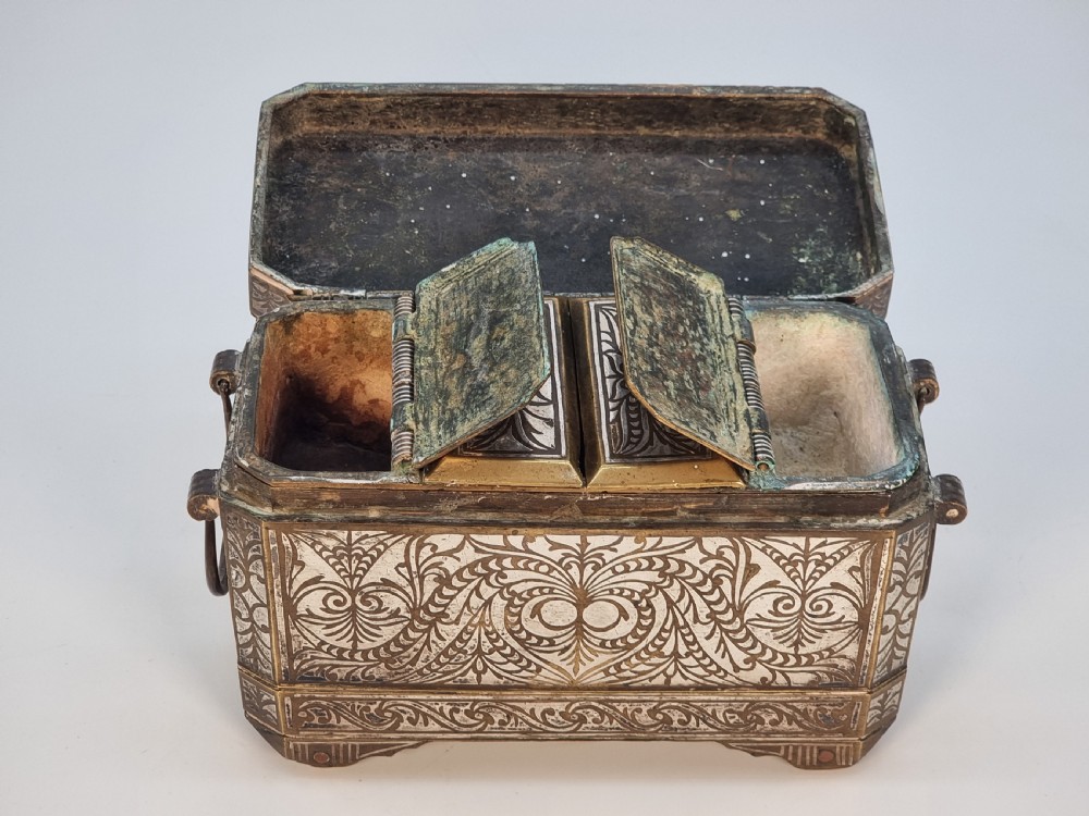 A rectangular dark bronze box featuring elaborate silver scrollwork inlay, side carrying handles, and small bracket feet. View XVIII
