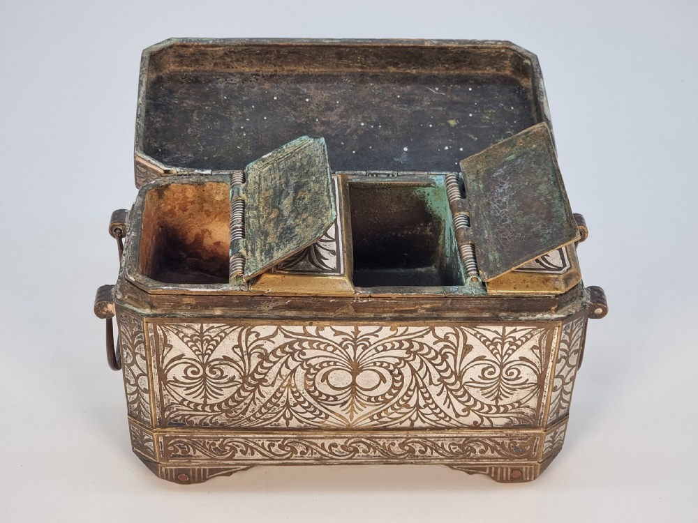 A rectangular dark bronze box featuring elaborate silver scrollwork inlay, side carrying handles, and small bracket feet. View XXI