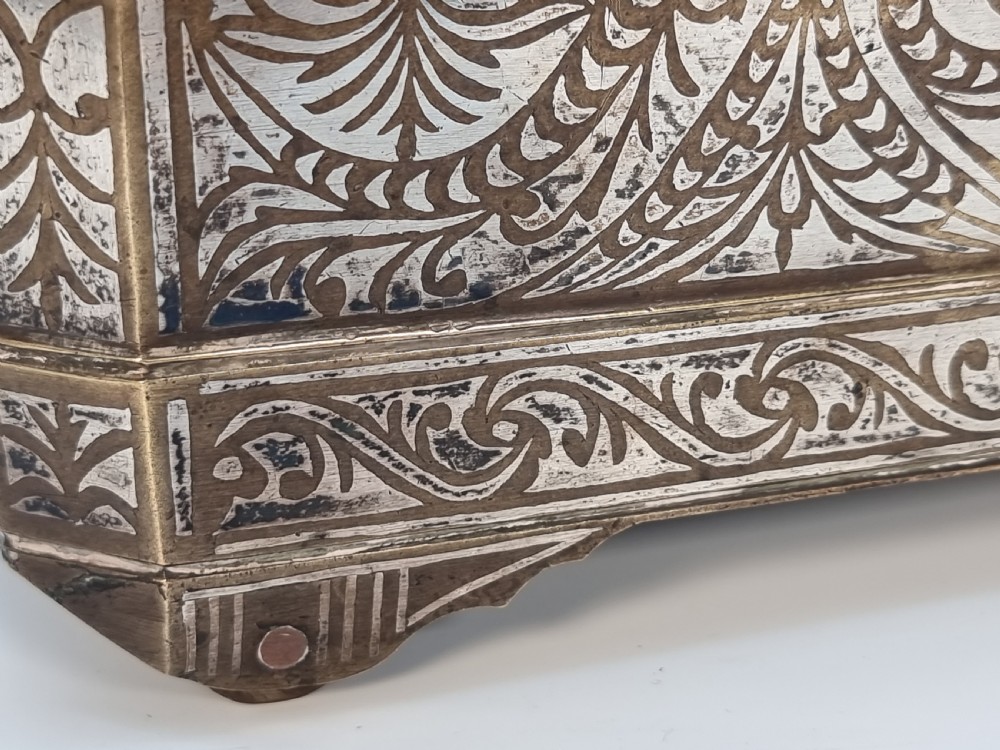 A rectangular dark bronze box featuring elaborate silver scrollwork inlay, side carrying handles, and small bracket feet. View XXVII