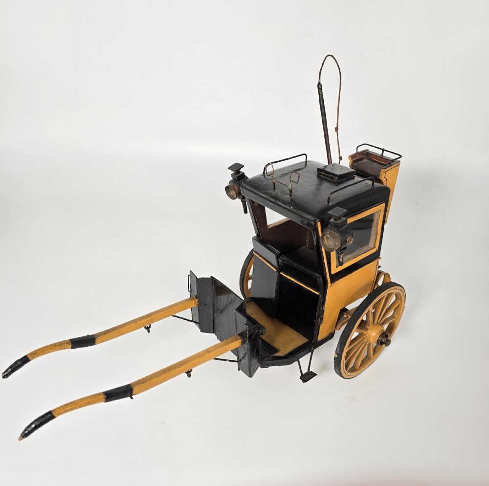 A detailed yellow and black wooden scale model of a two-wheeled 19th-century Hansom cab carriage. View IV
