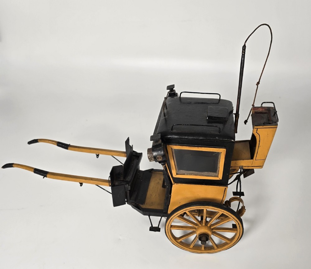 A detailed yellow and black wooden scale model of a two-wheeled 19th-century Hansom cab carriage. View V