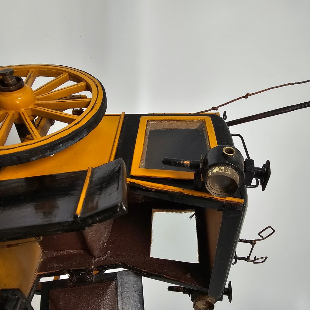 A detailed yellow and black wooden scale model of a two-wheeled 19th-century Hansom cab carriage. View XI