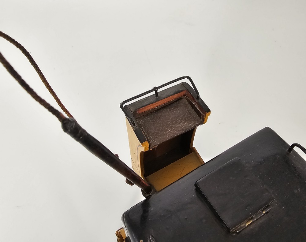 A detailed yellow and black wooden scale model of a two-wheeled 19th-century Hansom cab carriage. View XII