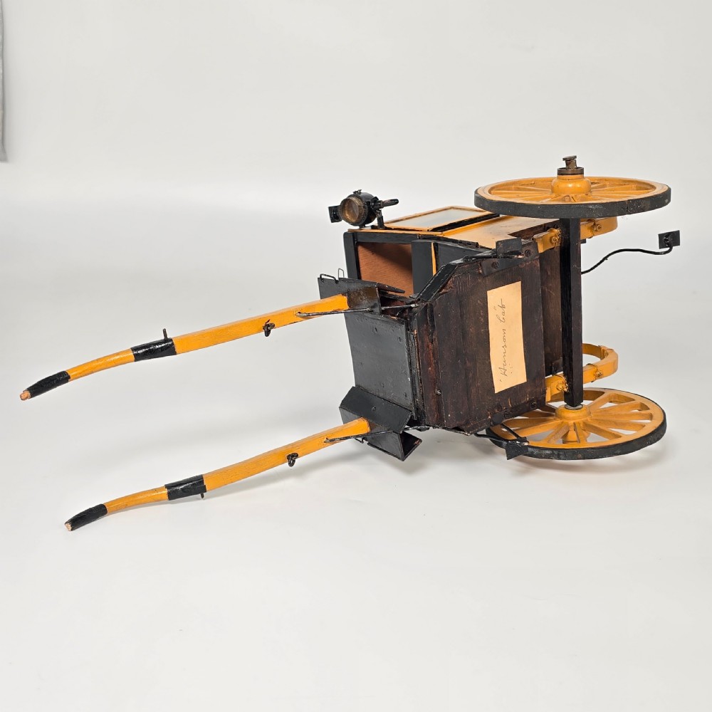 A detailed yellow and black wooden scale model of a two-wheeled 19th-century Hansom cab carriage. View XVI