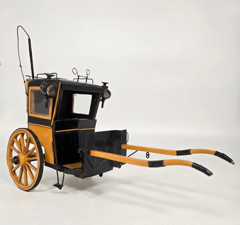 A detailed yellow and black wooden scale model of a two-wheeled 19th-century Hansom cab carriage. View XVII