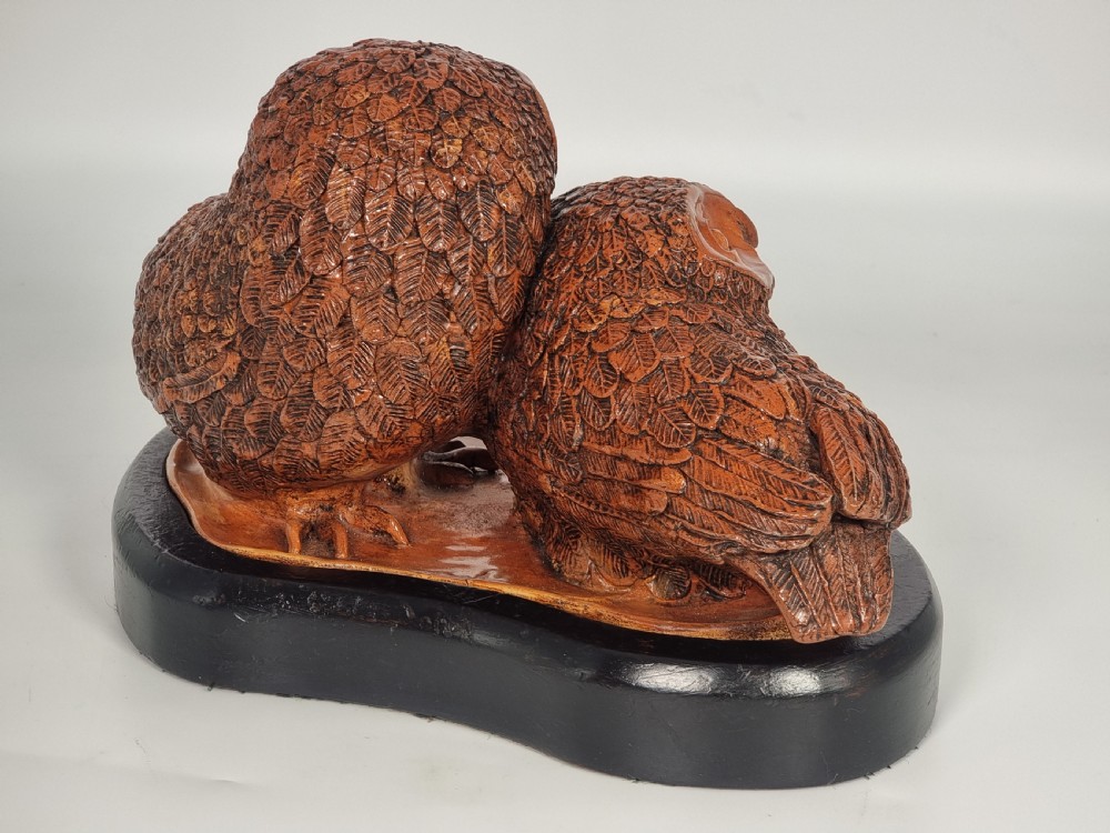 A hand-sculpted brown glazed pottery figurine of two owls perched together on a black ebonised wooden base. View VI