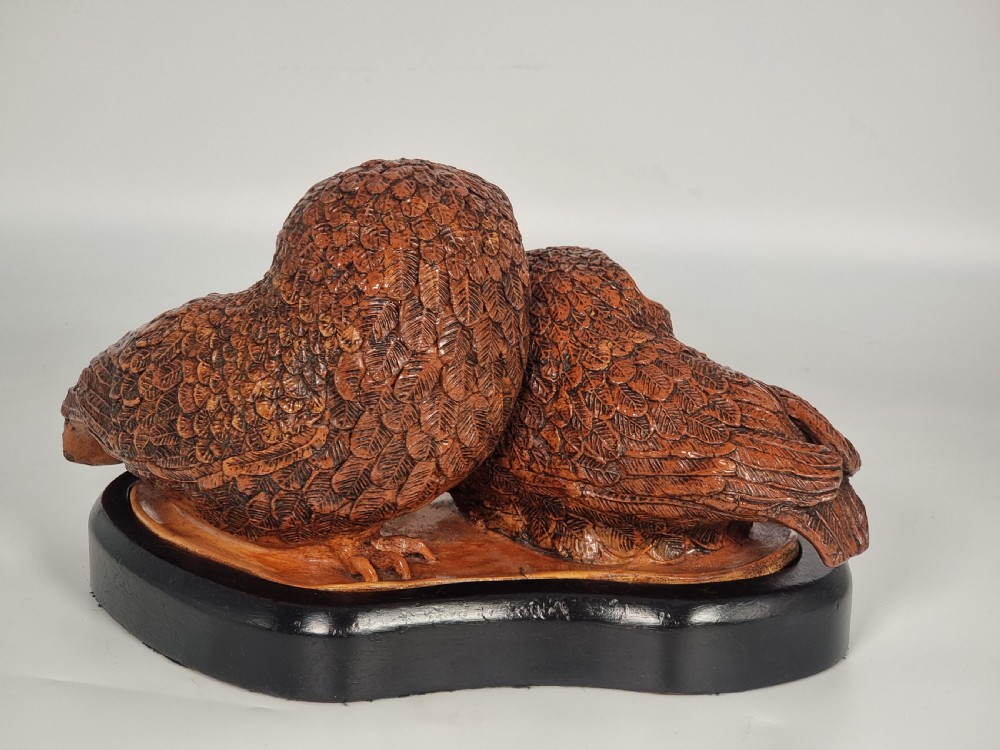 A hand-sculpted brown glazed pottery figurine of two owls perched together on a black ebonised wooden base. View VII