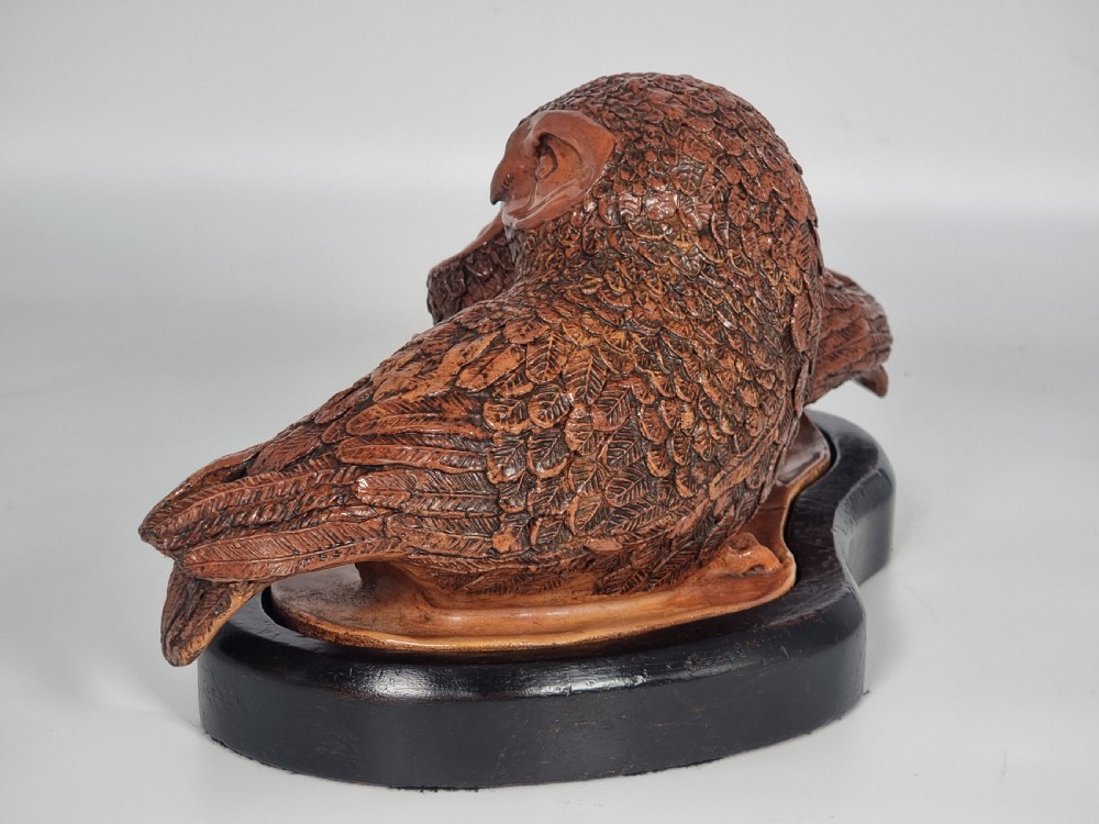 A hand-sculpted brown glazed pottery figurine of two owls perched together on a black ebonised wooden base. View VIII