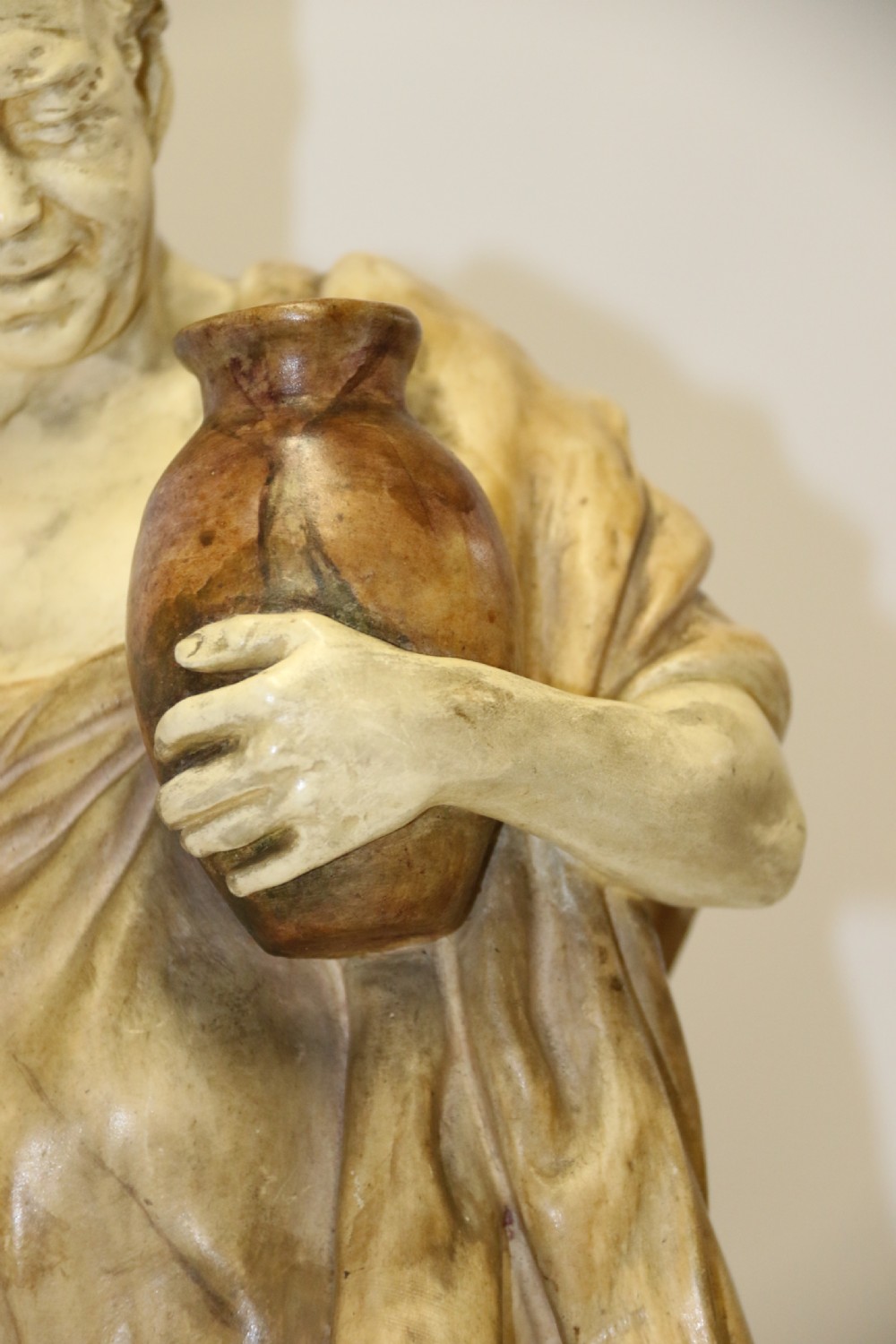 A 19th-century Goldscheider terracotta sculpture depicting a classical Roman male figure draped in robes, holding a vessel in one hand and a harvested bird in the other. View IV