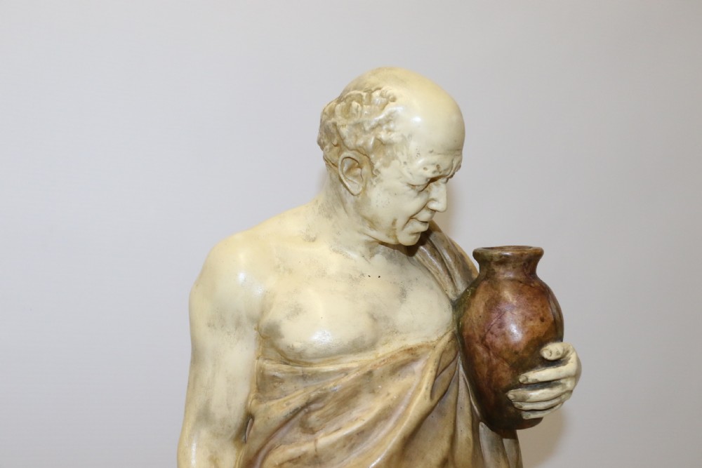 A 19th-century Goldscheider terracotta sculpture depicting a classical Roman male figure draped in robes, holding a vessel in one hand and a harvested bird in the other. View VIII