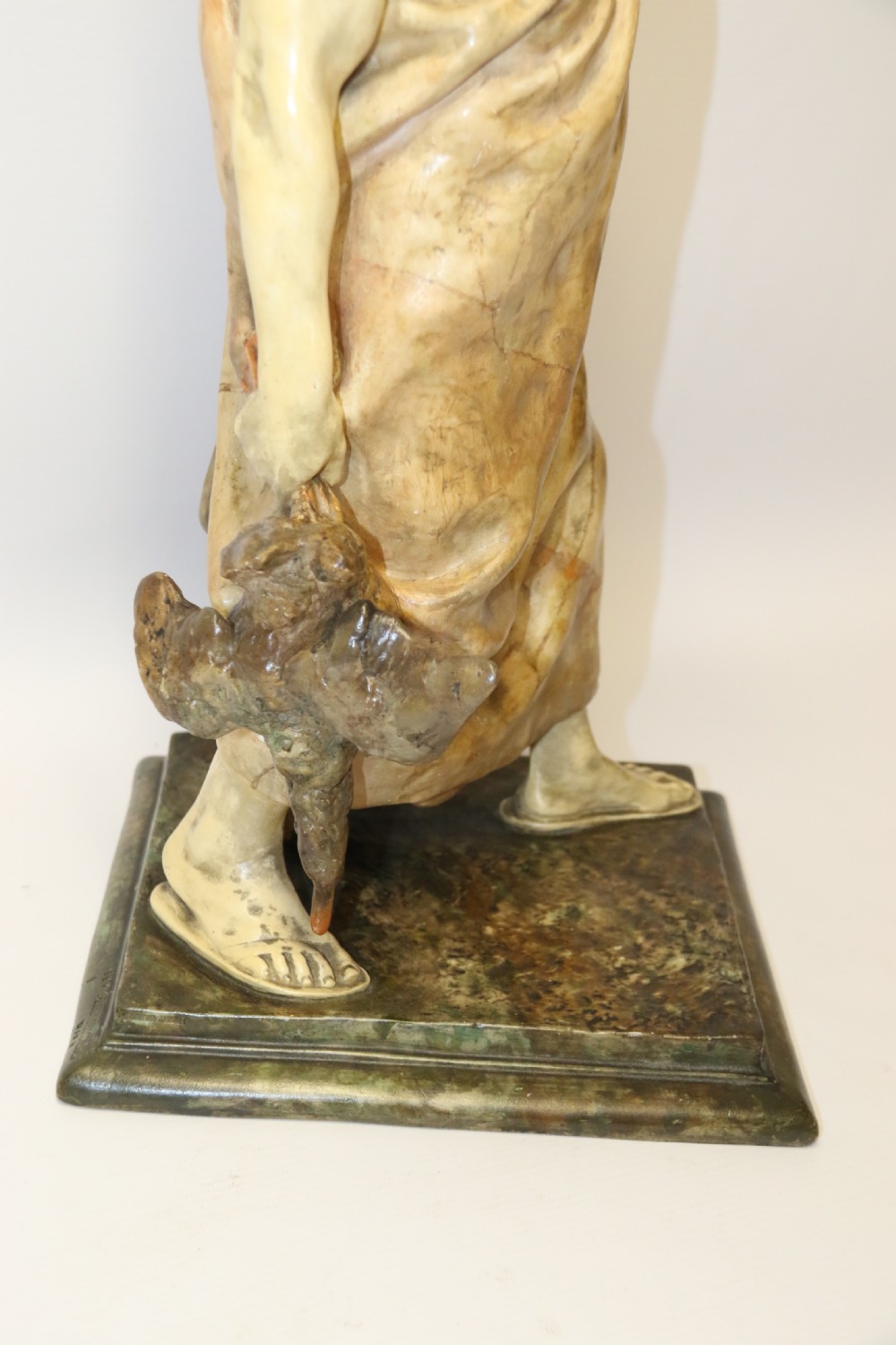 A 19th-century Goldscheider terracotta sculpture depicting a classical Roman male figure draped in robes, holding a vessel in one hand and a harvested bird in the other. View IX