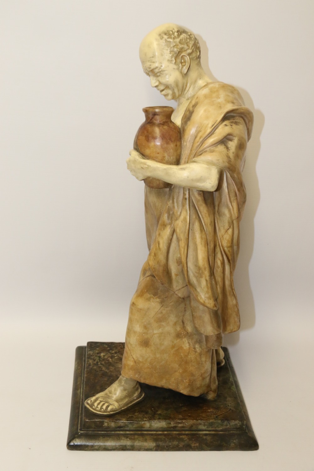 A 19th-century Goldscheider terracotta sculpture depicting a classical Roman male figure draped in robes, holding a vessel in one hand and a harvested bird in the other. View XII