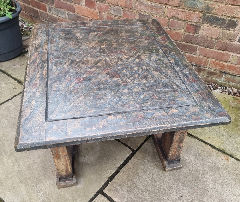 A low square rustic oak coffee table featuring a dark hand-painted geometric top and heavy timber legs. View IX