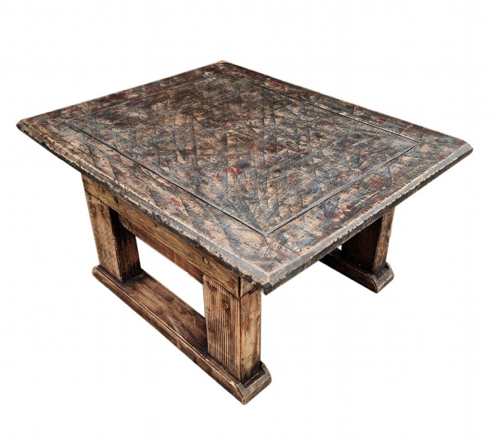 A low square rustic oak coffee table featuring a dark hand-painted geometric top and heavy timber legs.