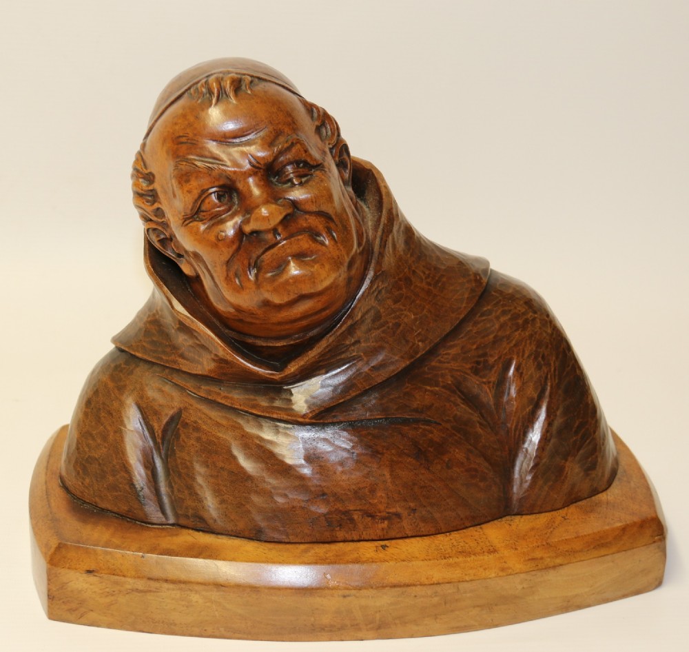 A late 19th-century hand-carved walnut study bust depicting a hooded monk on a moulded wooden base.