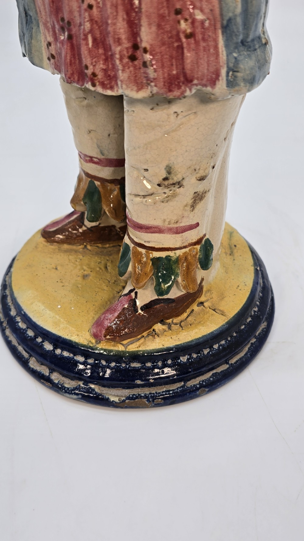 A polychrome glazed earthenware figure of a masked Commedia dellArte Pulcinella holding a stringed instrument. View XV