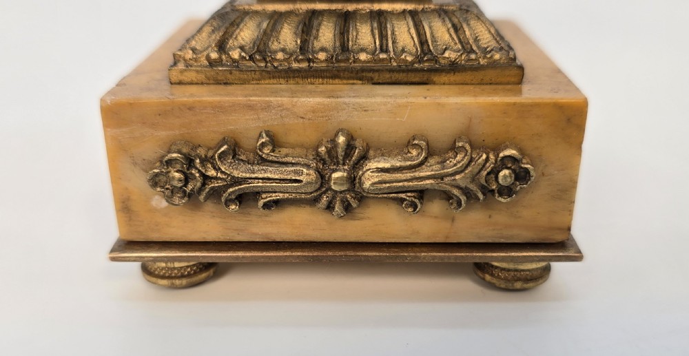 A pair of antique French Empire gilt bronze and yellow marble candlesticks featuring urn-shaped sconces, tapered rectangular pillars with floral appliques, and square bases on small ball feet. View XVI