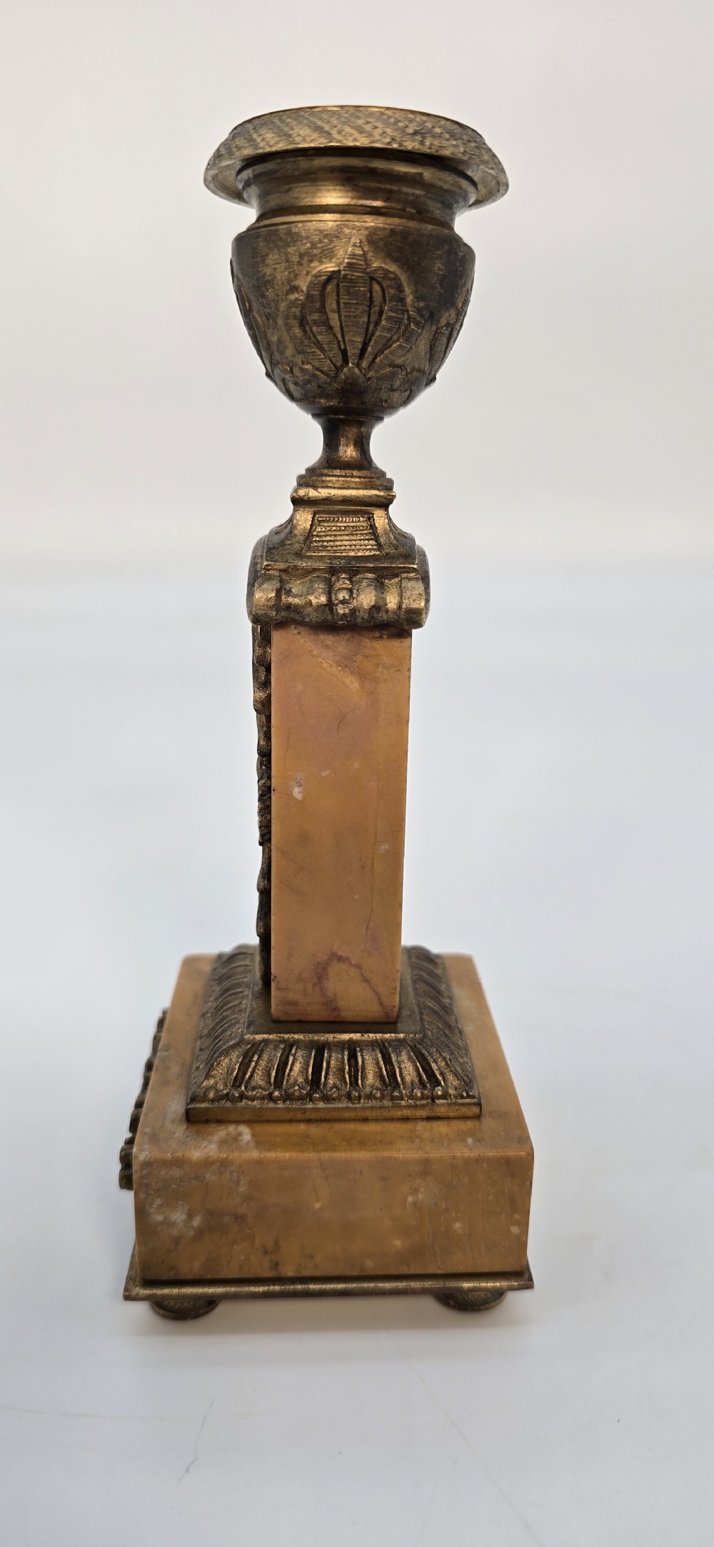 A pair of antique French Empire gilt bronze and yellow marble candlesticks featuring urn-shaped sconces, tapered rectangular pillars with floral appliques, and square bases on small ball feet. View XIX