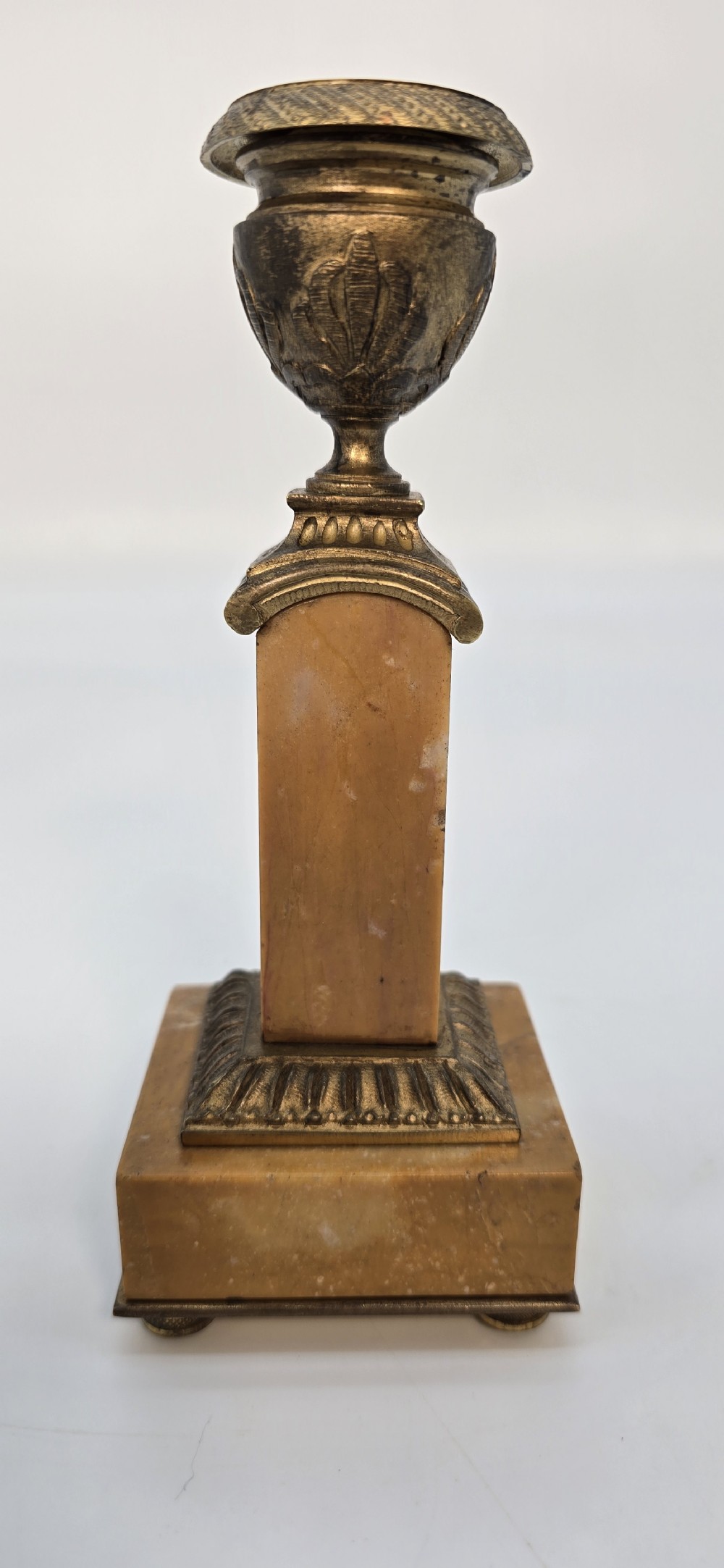 A pair of antique French Empire gilt bronze and yellow marble candlesticks featuring urn-shaped sconces, tapered rectangular pillars with floral appliques, and square bases on small ball feet. View XXI