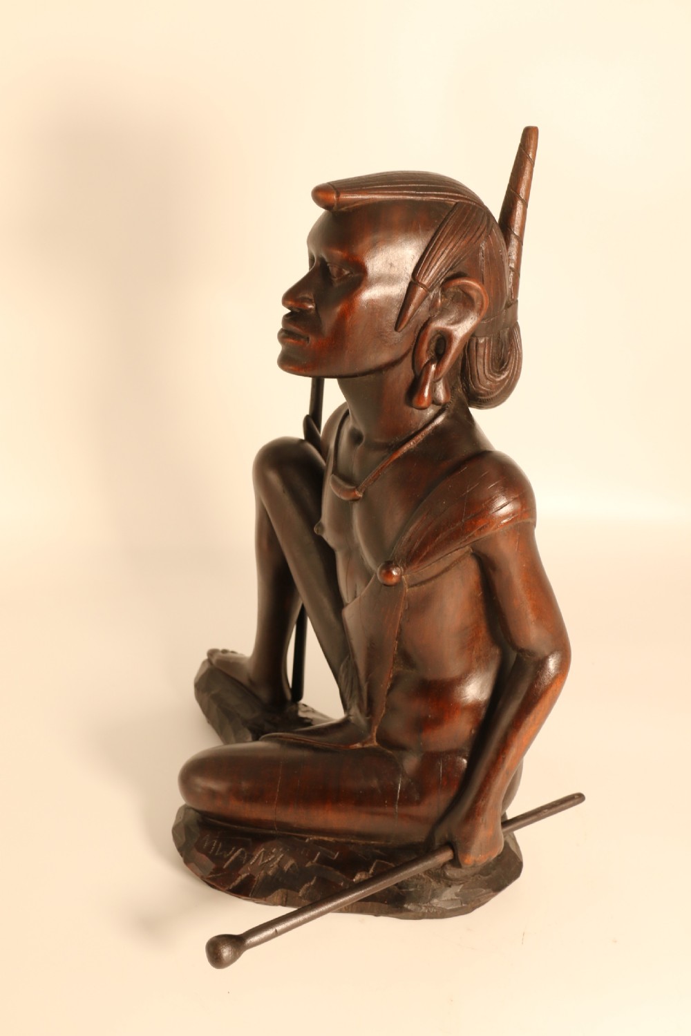 A dark hardwood hand-carved sculpture of a kneeling Maasai warrior holding a spear and club on an integrated wooden base. View VIII