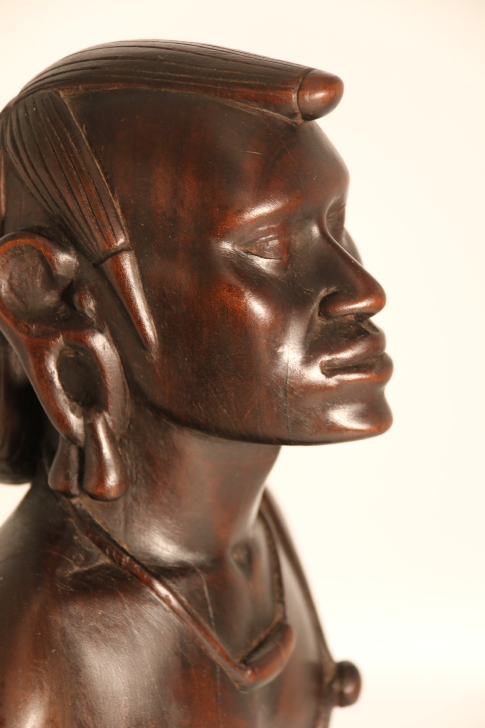 A dark hardwood hand-carved sculpture of a kneeling Maasai warrior holding a spear and club on an integrated wooden base. View XIII