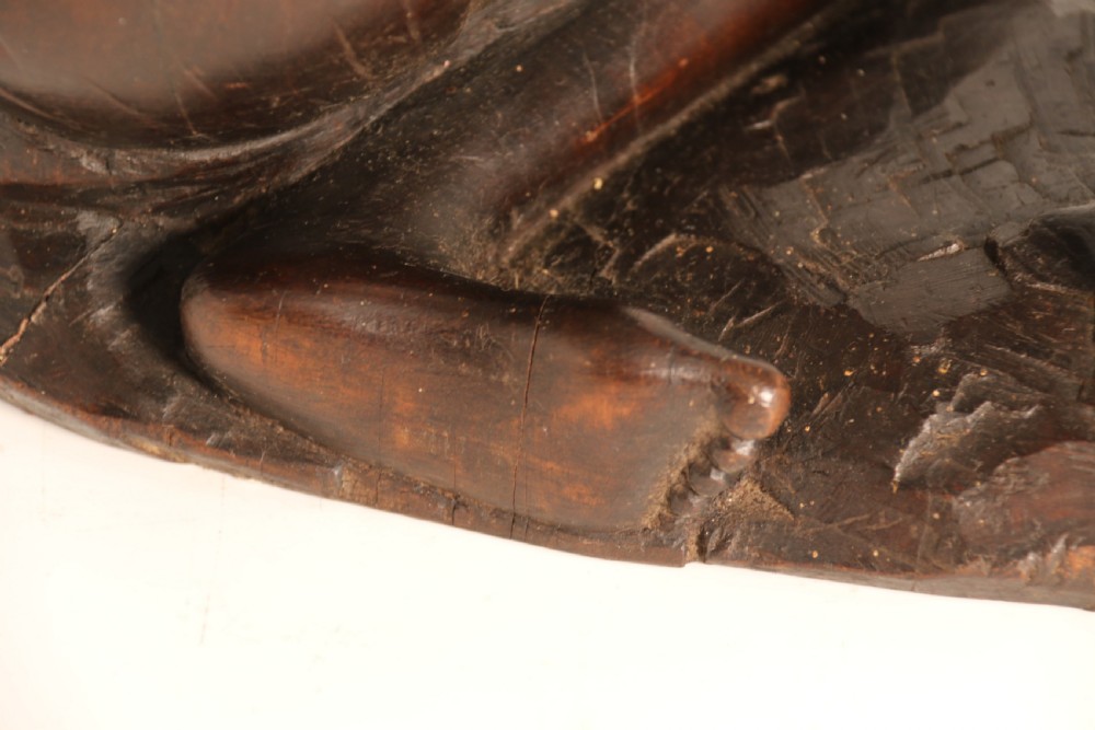 A dark hardwood hand-carved sculpture of a kneeling Maasai warrior holding a spear and club on an integrated wooden base. View XVII