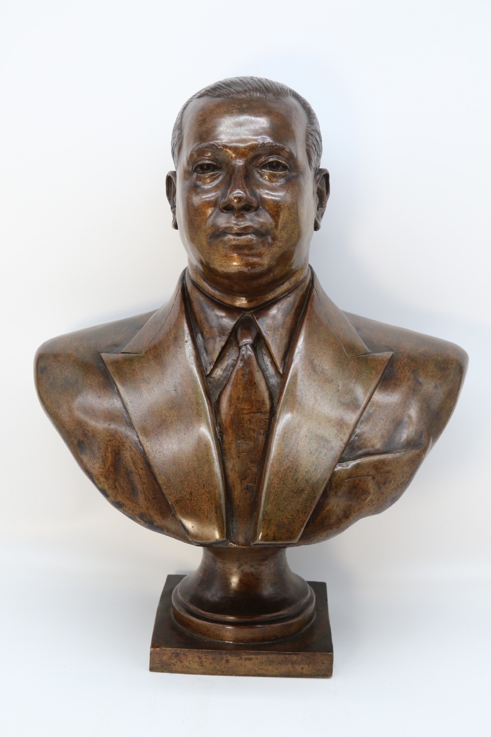 A cast bronze portrait bust depicting a gentleman in a suit jacket and tie, resting on a pedestal base with a square plinth. View II