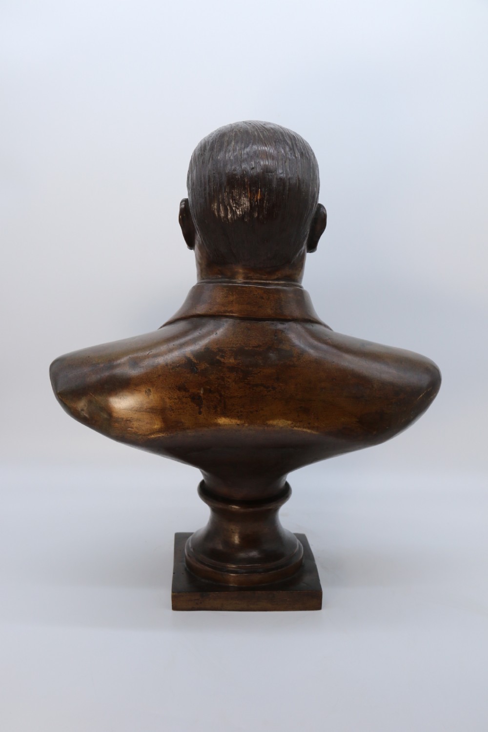 A cast bronze portrait bust depicting a gentleman in a suit jacket and tie, resting on a pedestal base with a square plinth. View VII