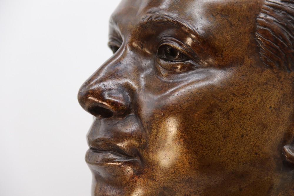 A cast bronze portrait bust depicting a gentleman in a suit jacket and tie, resting on a pedestal base with a square plinth. View XVI
