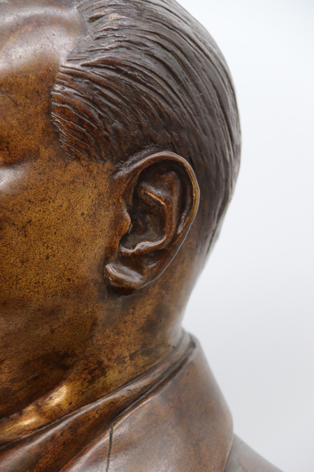 A cast bronze portrait bust depicting a gentleman in a suit jacket and tie, resting on a pedestal base with a square plinth. View XVII