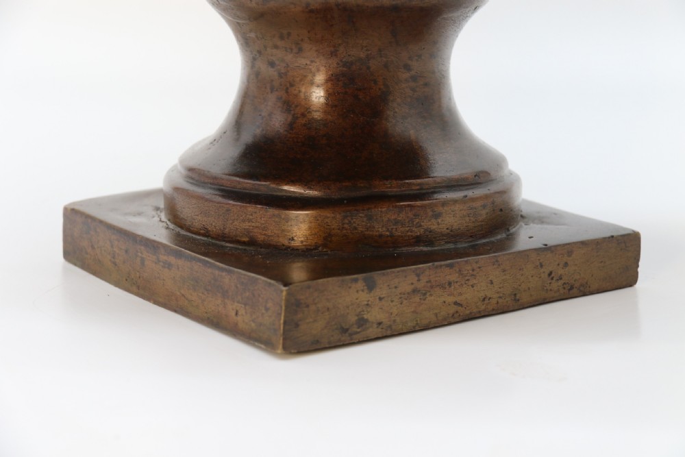 A cast bronze portrait bust depicting a gentleman in a suit jacket and tie, resting on a pedestal base with a square plinth. View XVIII