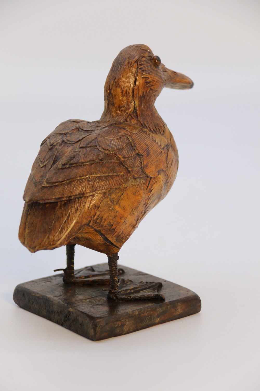 A small folk art duckling sculpture crafted from papier mache and textured straw, mounted on a square wooden base. View IV