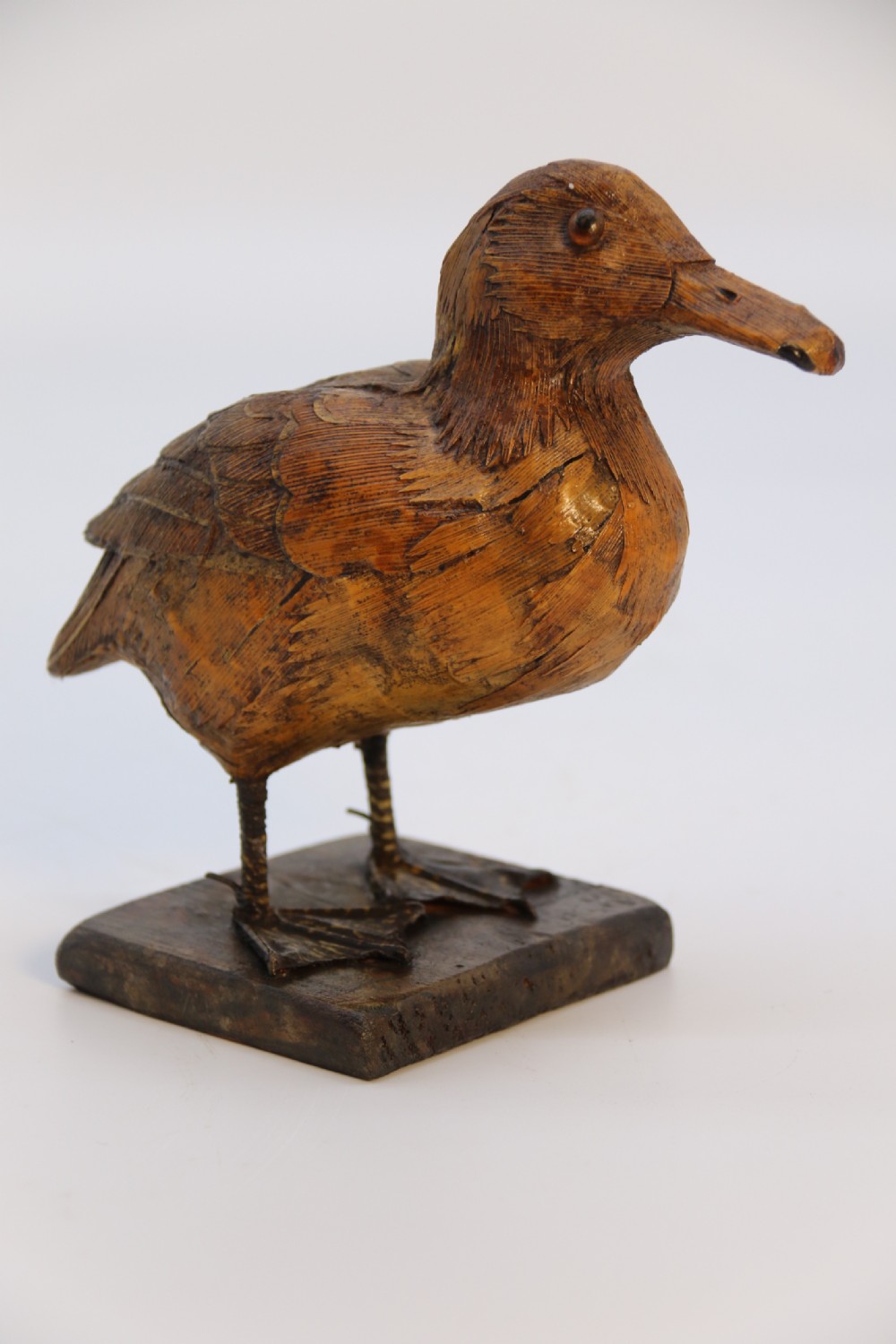 A small folk art duckling sculpture crafted from papier mache and textured straw, mounted on a square wooden base. View VII