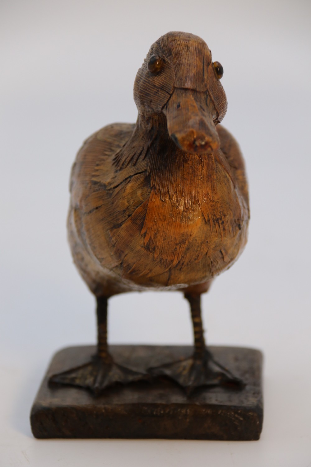 A small folk art duckling sculpture crafted from papier mache and textured straw, mounted on a square wooden base. View VIII