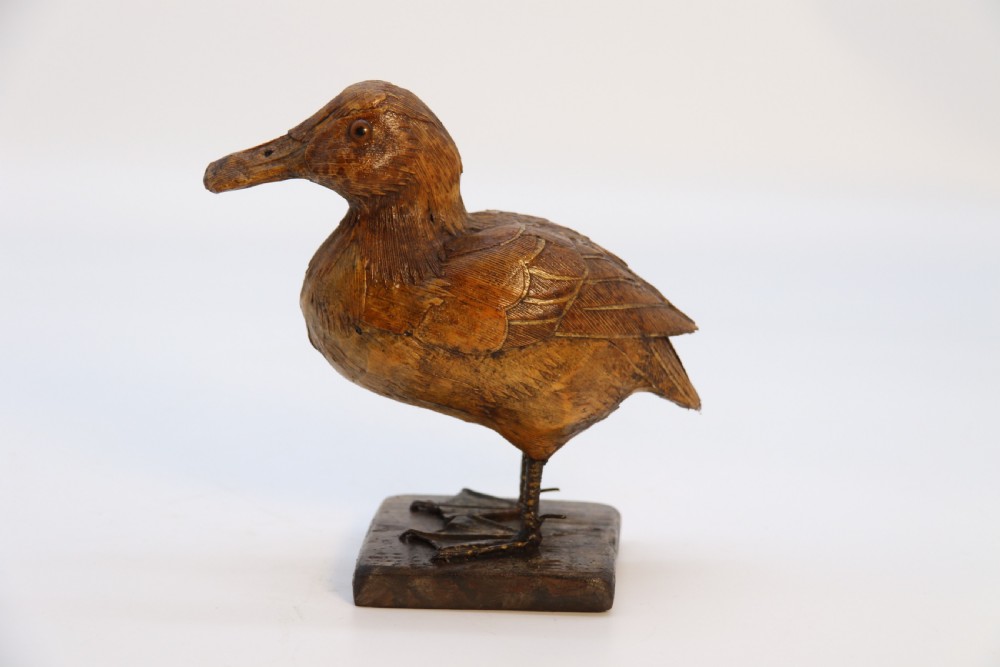 A small folk art duckling sculpture crafted from papier mache and textured straw, mounted on a square wooden base. View IX