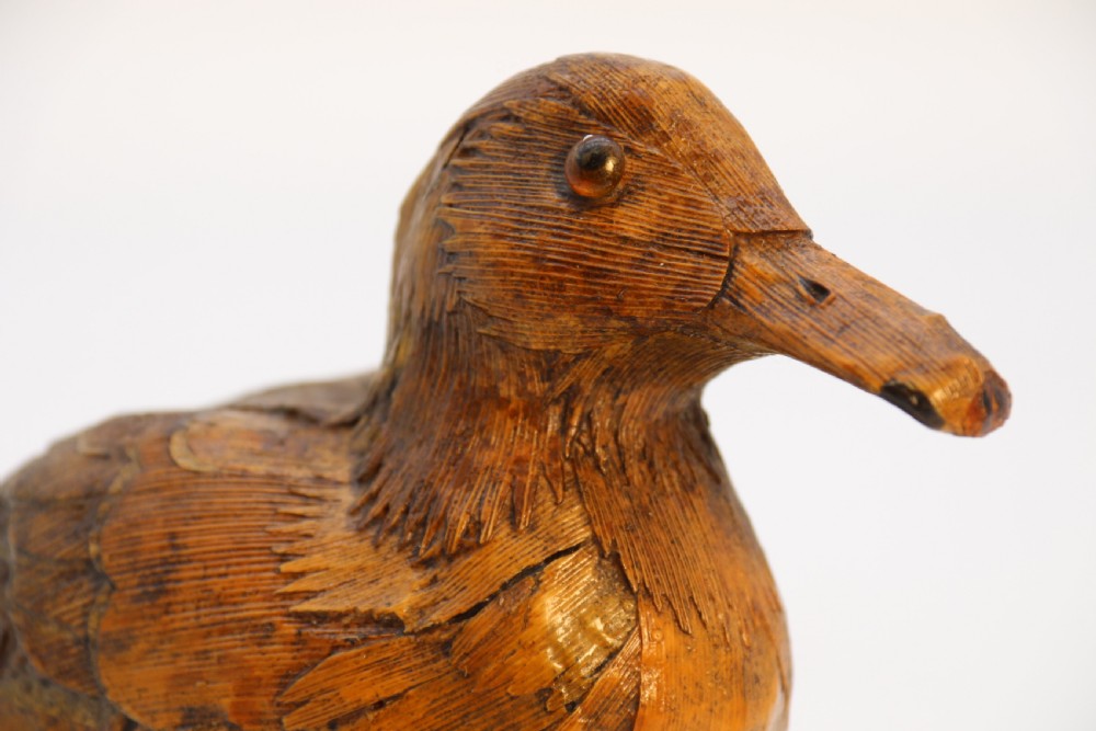 A small folk art duckling sculpture crafted from papier mache and textured straw, mounted on a square wooden base. View XI