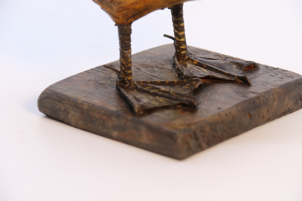 A small folk art duckling sculpture crafted from papier mache and textured straw, mounted on a square wooden base. View XIII