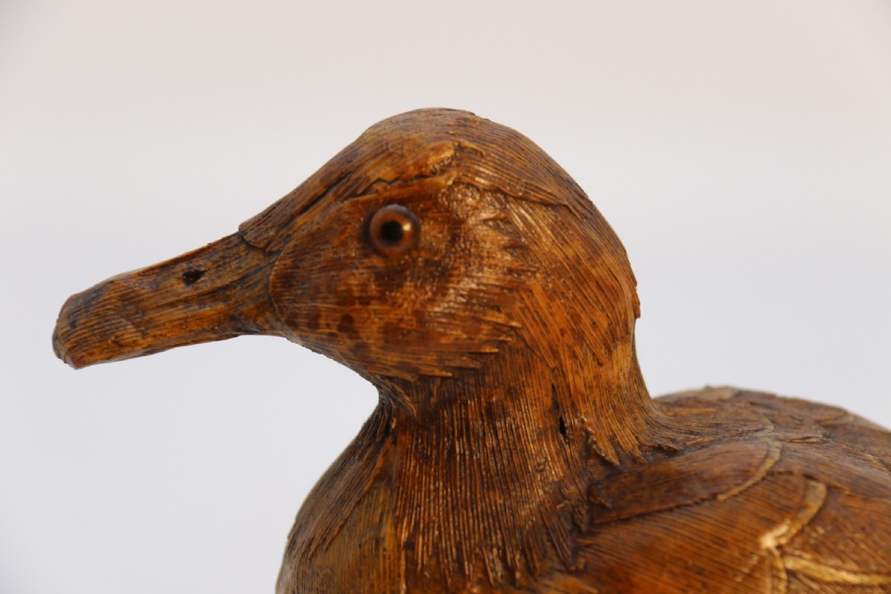A small folk art duckling sculpture crafted from papier mache and textured straw, mounted on a square wooden base. View XVII