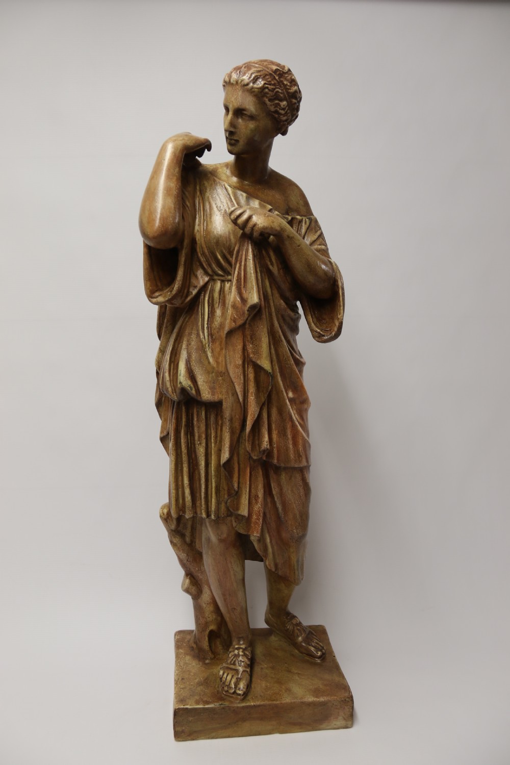 A nineteenth-century Neoclassical sculpture depicting Diana the Huntress draped in classical robes standing on a square base with a warm beige patinated finish. View II